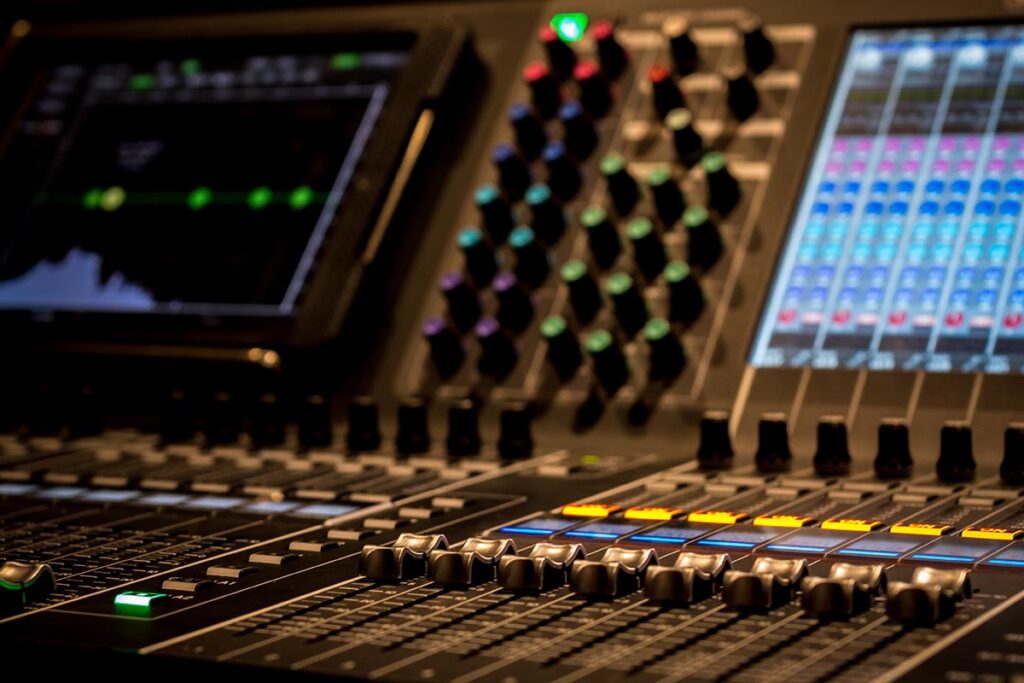 Wide angle closeup of Professional Digital Audio Sound Mixing Control Console. Silver White Faders and black Graphic control Console, touchscreen control and digital encoders